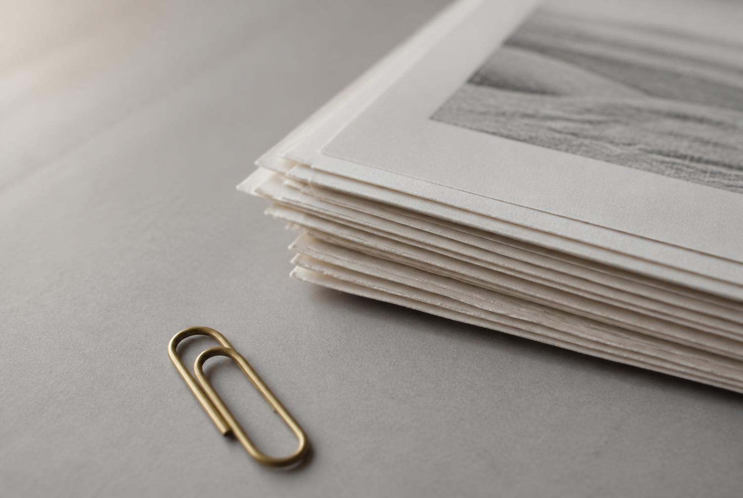 Feuilles de papier et plaque de laiton posées sur une pierre claire